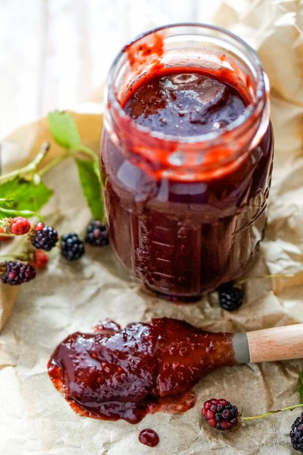 A jar of blackberry bbq sauce with a basting brush to one side.