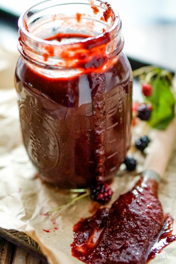 A jar of blackberry bbq sauce with a basting brush to one side.
