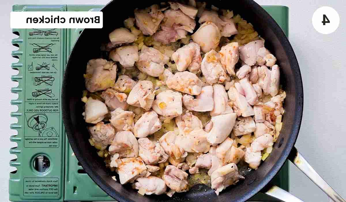 chicken cubes being browed in a frying pan with caption