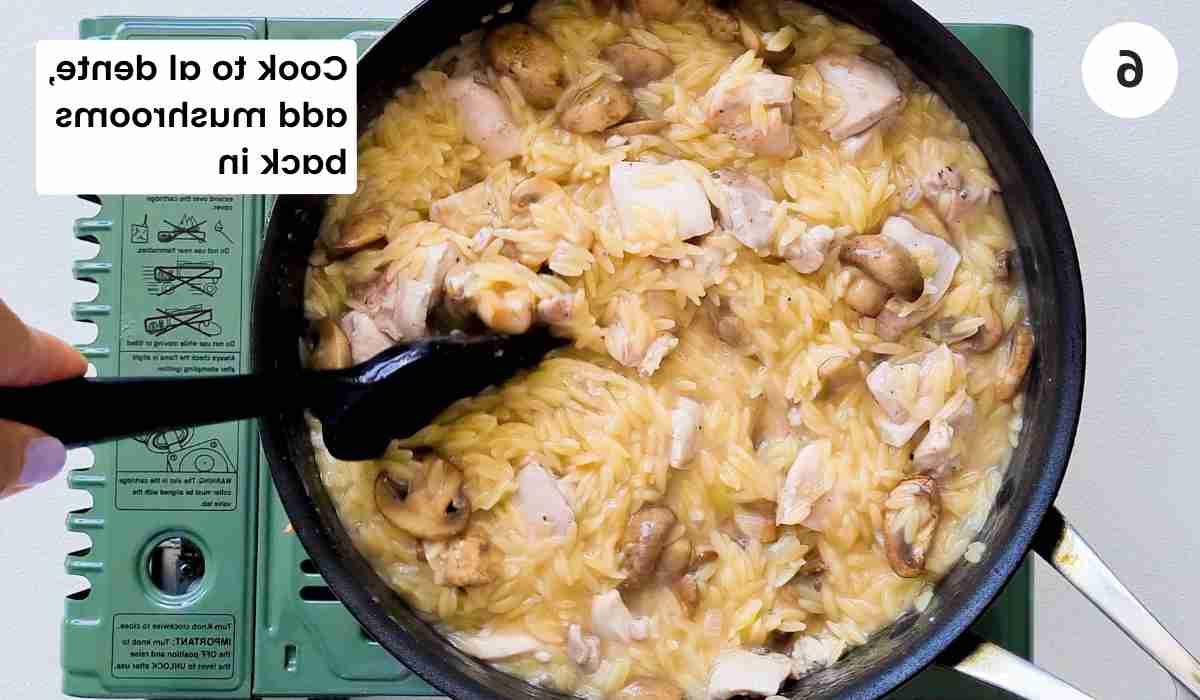 orzo, chicken and mushrooms being stirred in a saute pan