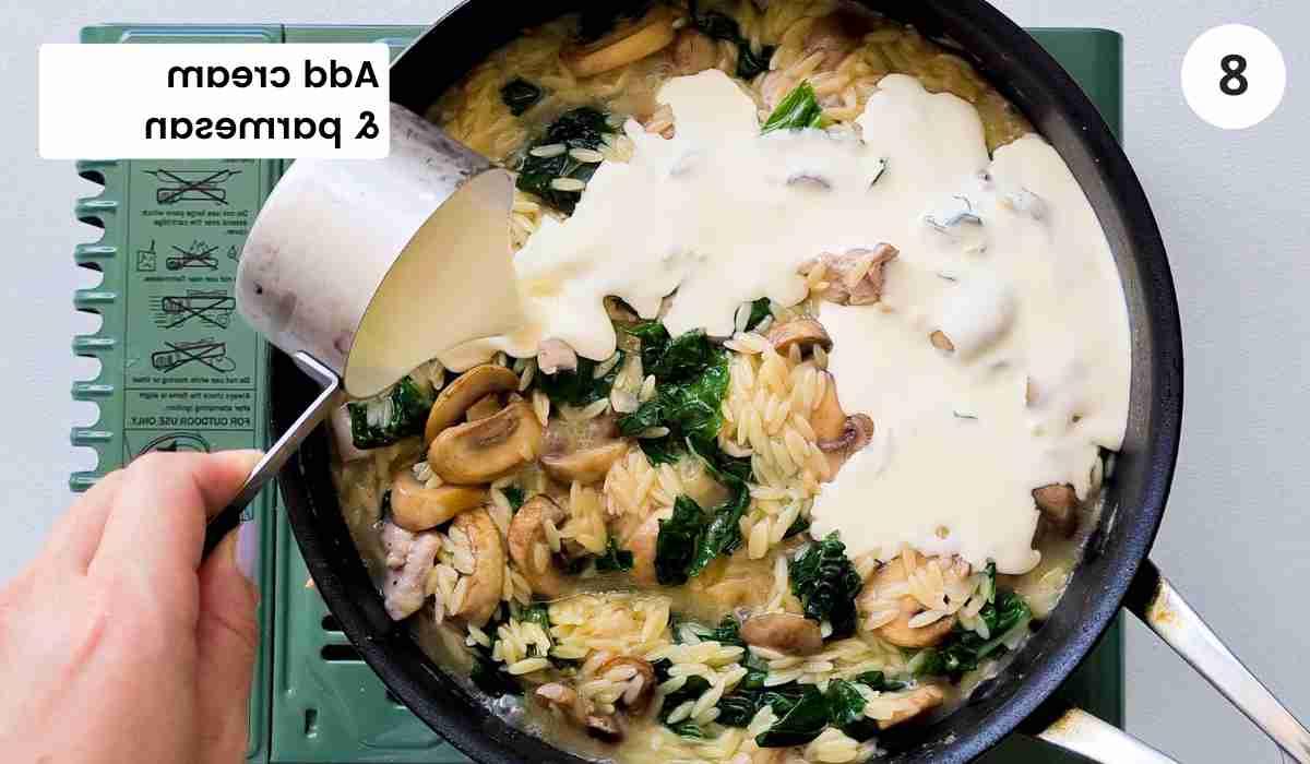 Heavy cream being poured into a pan of pasta with caption