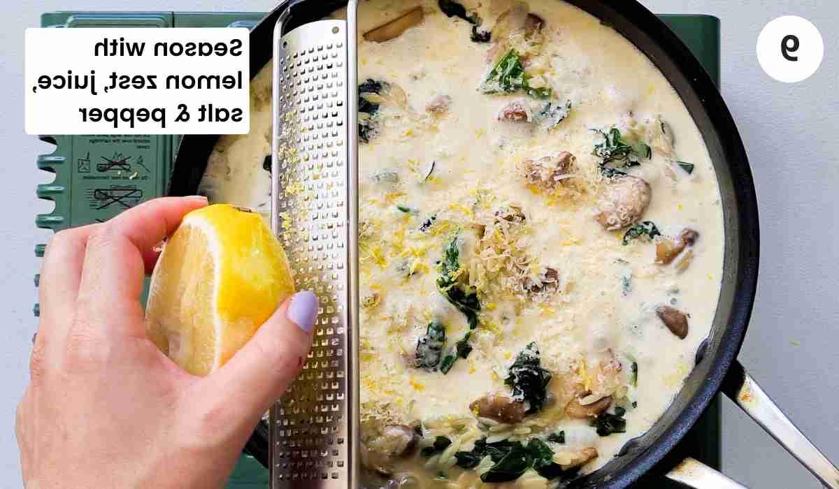 lemon being zested into a saute pan filled with creamy pasta