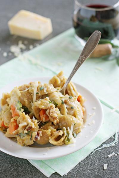 A white dish filled with Butternut Squash Pasta Sauce and shells with a fork in the dish.
