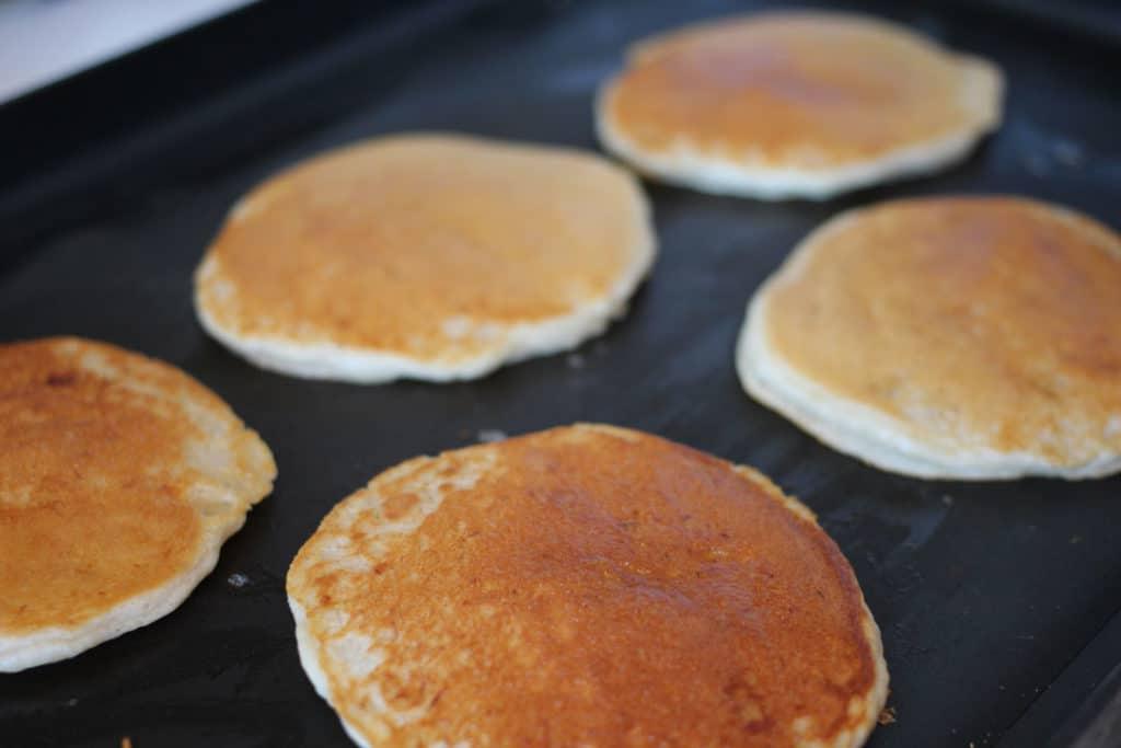 Pancakes cooking on the griddle.