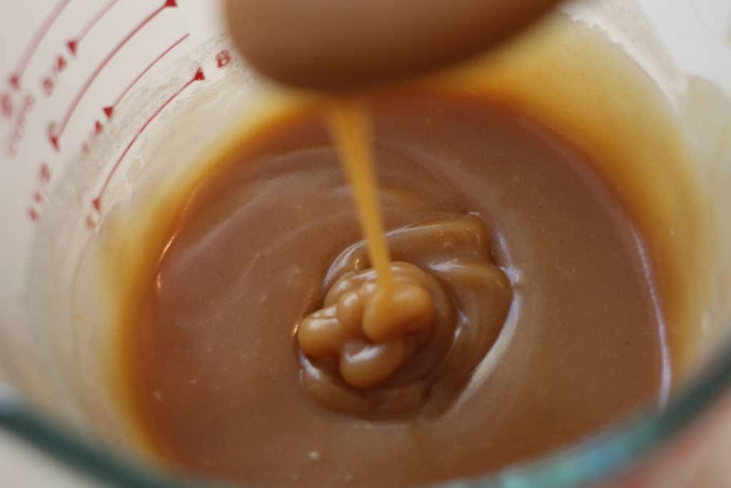Peanut butter pancake syrup dripping off of a spoon.